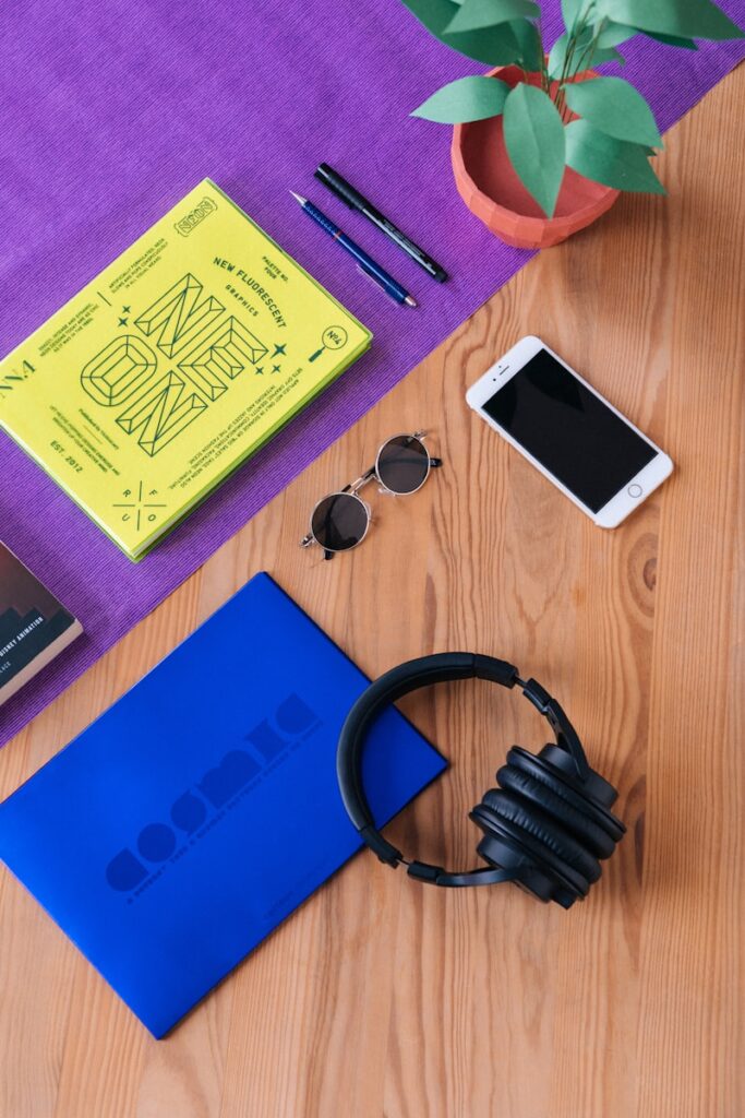 headphones near sunglasses, iPhone 6, and pens on wooden surface